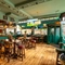 The bar and interior restaurant seating area at the Phoenix, with wooden flooring, bar stool seating, and a large TV hanging on the wall above the windows.