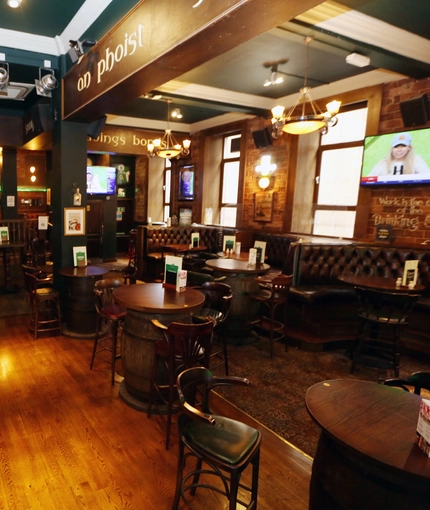 The bar and seating areas of Molly Malones, with a televison on the wall.