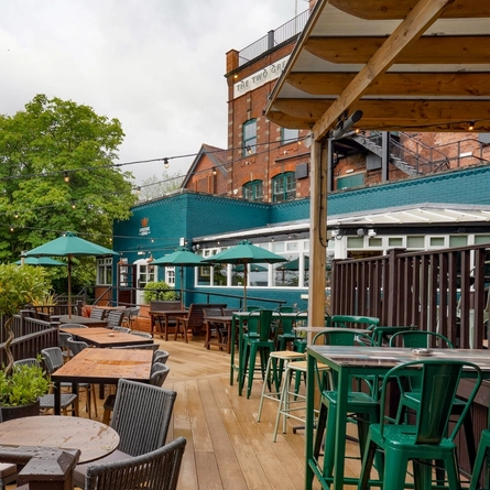 The exterior beer garden seating area with partial undercover section and rear of the venue at The Two Greens.