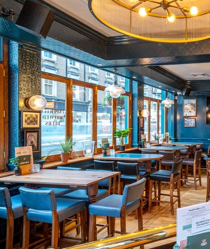 The interior restaurant seating area of The Earls Court Tavern, with a TV on the wall.
