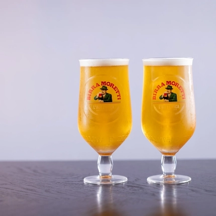 two pints of Moretti beer sitting on a wooden table