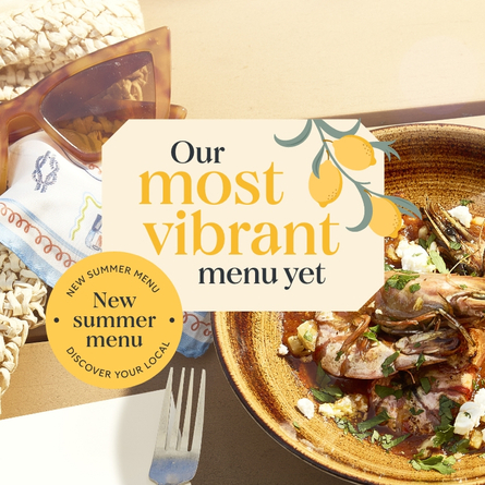 A banner showing a close up image of a seafood dish sat on a table within the exterior beer garden seating area to advertise the new summer menu at Chef & Brewer venues.
