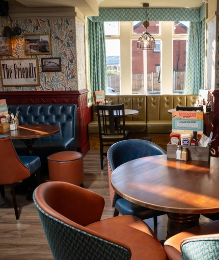 The interior restaurant seating area of The Horsforth, with framed artwork on the walls, and upholstered booth seating.