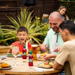A family seated at an outdoor table in a beer garden, enjoying a meal.