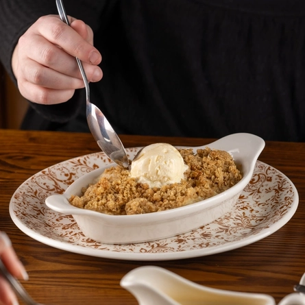 Plates of Apple Crumble on a wooden table of a pub