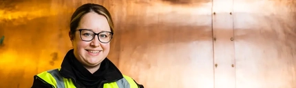 An apprentice posing in front of machinery.