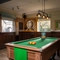 The interior pub gaming area of The Longship, with a dartboard, a pool table, and bar stool seating.