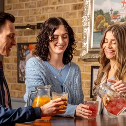 People drinking cocktails, pouring out of jugs into lowball glasses.
