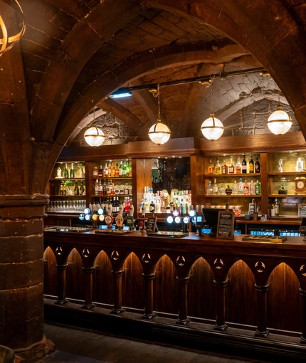 An image showing the interior bar area with wooden gothic arched carvings and stone vaulted ceiling at The Watergates Bar.