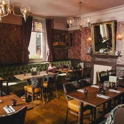 Interior restaurant and dining area of the Sherlock holmes venue, with a fire place and wallpapered walls