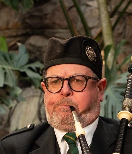 A Bagpipe Player stood within the interior restaurant seating area at The Ubiquitous Chip.