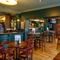 The ground floor bar and interior restaurant seating area at The Globe; with checkerboard tiles in front of the counter, TVs on the walls, two gaming machines, and bar stool seating.