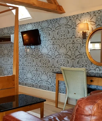 The interior hotel kingsize bedroom with kingsize four poster bed, a sofa, mirror, dressing table and coffee table at the Fox.