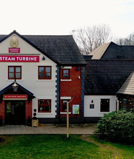 The exterior facade, signage, and accessible car park area at The Steam Turbine in Rugby.