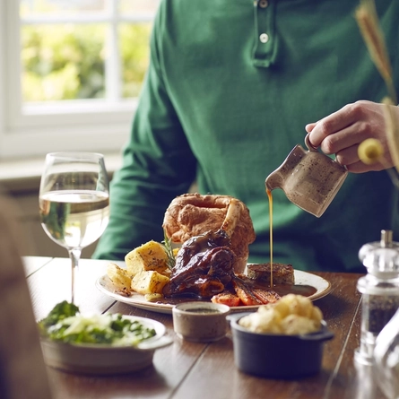 Gravy being poured onto a roast dinner.