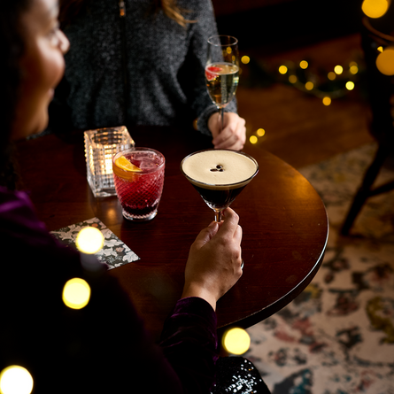 An image of 2 drinks being held and one sat on a table within the interior restaurant and seating area at a Chef & Brewer venue.