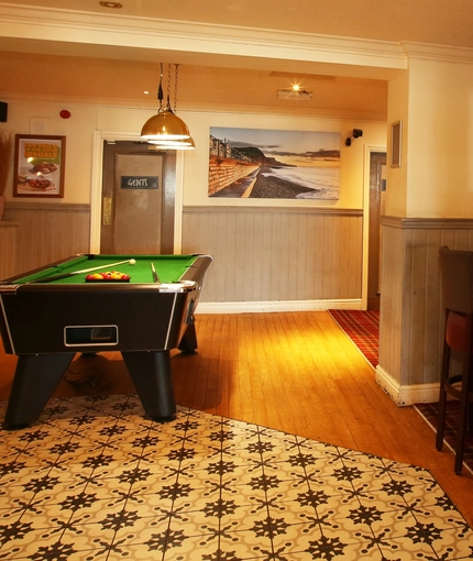 Interior dining area of a pub with a pool table.