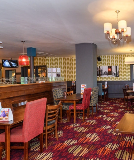 Interior dining area of a pub with a fireplace and a TV.