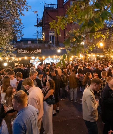 An evening image of crowds stood within the beer garden area during The Boat Race event at The Crabtree.