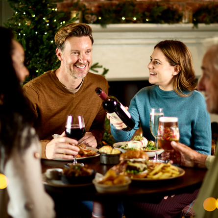 An image of 4 people sat around a table within the exterior restaurant and seating area enjoying various drinks and main dishes available at Chef & Brewer venues.