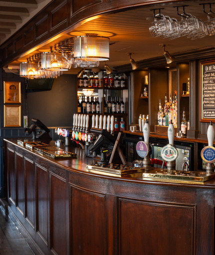 An image of the interior bar with wooden front panelling, ceiling beams and wooden flooring at The Spice Island.