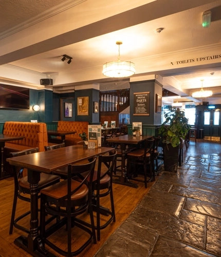An interior restaurant seating area at the Lord Raglan, with stone floor, upholstered booth seats, and a TV on the wall.