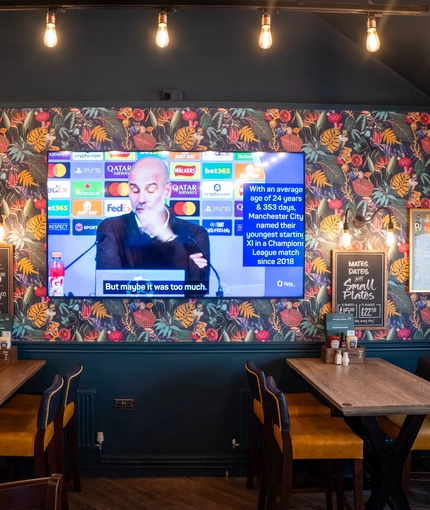 An interior restaurant seating area at The Grosvenor, with framed artwork and a TV on the wall.