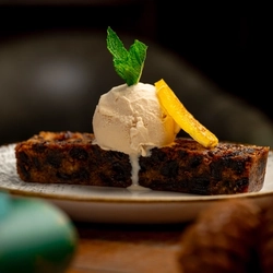 A plated slice of Christmas Pudding  on a wooden table.