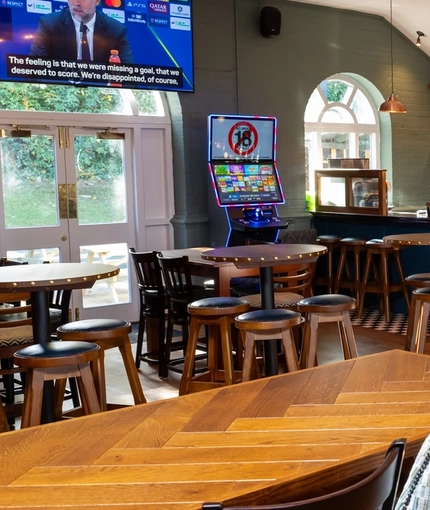 The bar and interior seating area of the Clocktower, with a TV on the wall, and pub gaming machines.