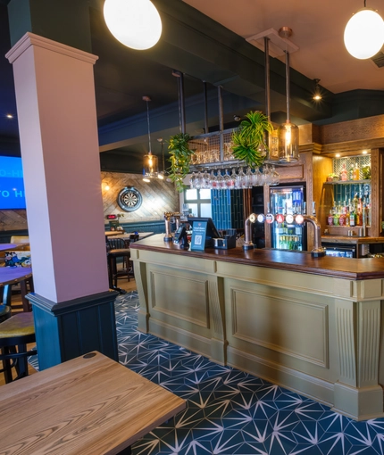 The bar and interior seating area at The Talbot Inn, with a dartboard, and a TV on the wall.