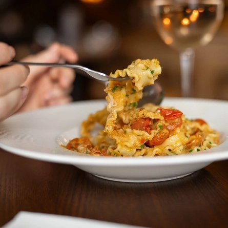 A lifestyle image showing a person lifting up a folk of Crab Mafalde from the Spring/Summer menu available at Metro venues.