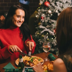 An image of 2 customers sat at a table enjoying festive main dishes and various drinks within the interior restaurant seating area at a Pub & Carvery venue.
