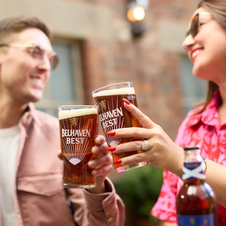 An image of 2 people enjoying Belhaven Best within the exterior beer garden seating area.