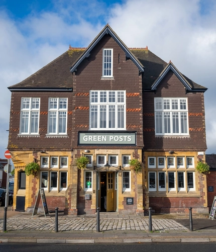 The exterior facade and signage of the Green Posts in Portsmouth, with hanging flowers baskets on the wall.