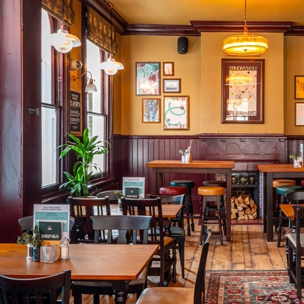 The interior restaurant seating area at The Fountains Abbey, with wooden tables and chairs, a TV on the wall, and a fireplace.