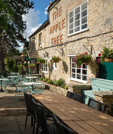 The exterior beer garden with benches, umbrellas and tables with chairs at the Apple Tree.