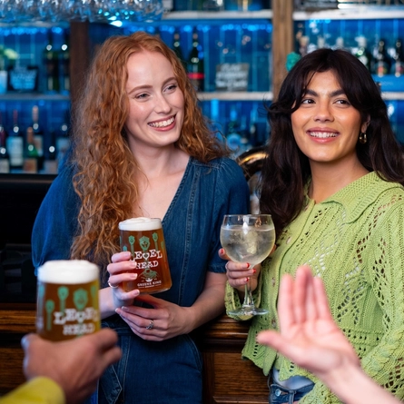 A group of people by the bar enjoying drinks.
