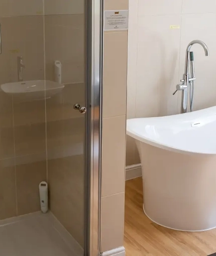 The interior hotel bathroom with a shower and bath at the Cedars Inn.