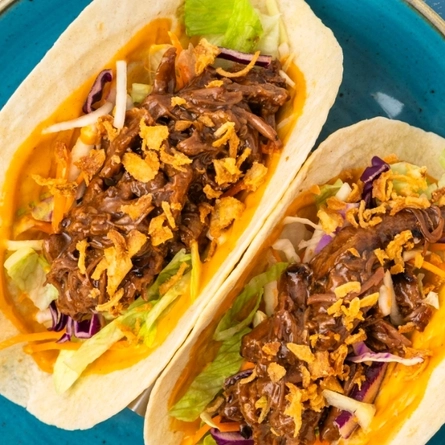 A starter of BBQ tacos served to advertise starters on offer at Flaming Grill venues on a textured green background.