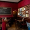 An interior restaurant seating area at the King's Head, with dark wood floors; textured red wallpaper; and framed artwork on the wall.
