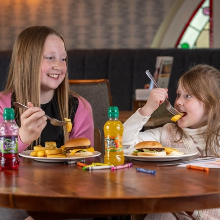 Two children enjoying kids meals served at a Flaming Grill venue.