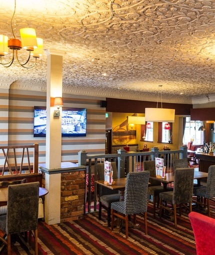 Interior dining area of a pub with a bar and a TV.