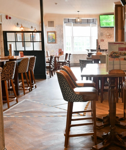 Interior dining area of a pub with a bar and a few TVs.