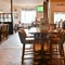 Interior dining area of a pub with a bar and a few TVs.