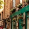The exterior facade, signage, and beer garden seating area of the Lucas Arms in London, with hanging flower baskets on the wall and wooden picnic tables.