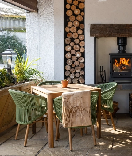 One of the restaurant seating areas at The Blue Cap in Sandiway, with a stone floor, wooden tables, and a log burner fireplace.