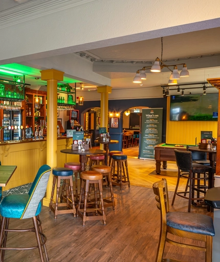 The bar and interior restaurant seating area of the Malvern Tavern, with a pool table, and a TV on the wall.