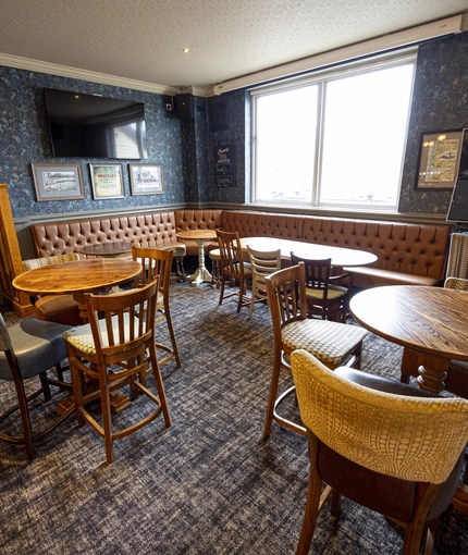 Interior dining area of a pub with a bar, a gambling machine and a TV.