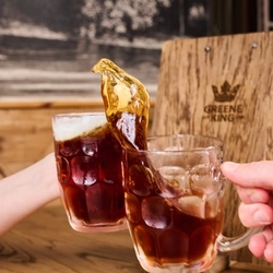2 People holding beer glasses doing a 'cheers' with beer spilling out of the glasses at a Premium Heritage venue.