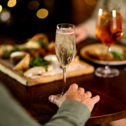 An image focusing on drinks with a sharer platter in the background within an interior restaurant and seating area at a Chef & Brewer venue.